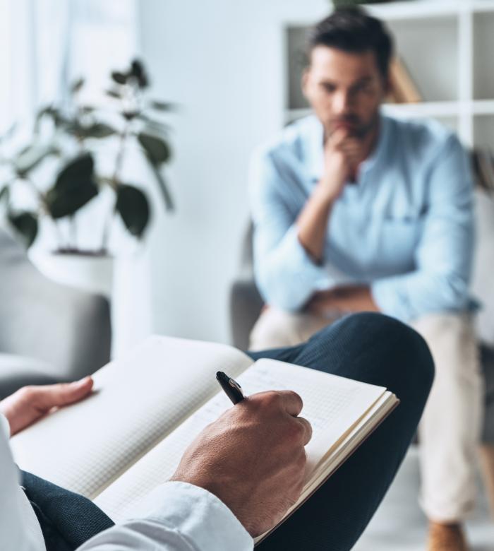 Making profile. Young frustrated man solving his mental problems while having therapy session with psychologist